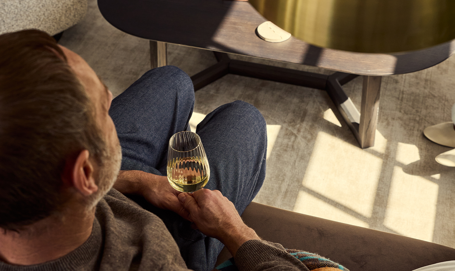 A man with a glass of drink in a serviced apartment in Pimlico, at Dolphin House at Dolphin Square.