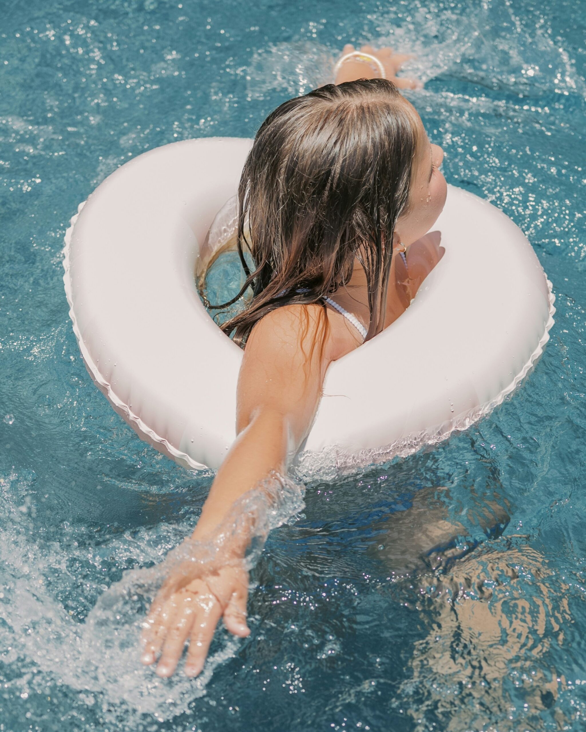 Child swimming with an inflatable ring in a swimming pool in London